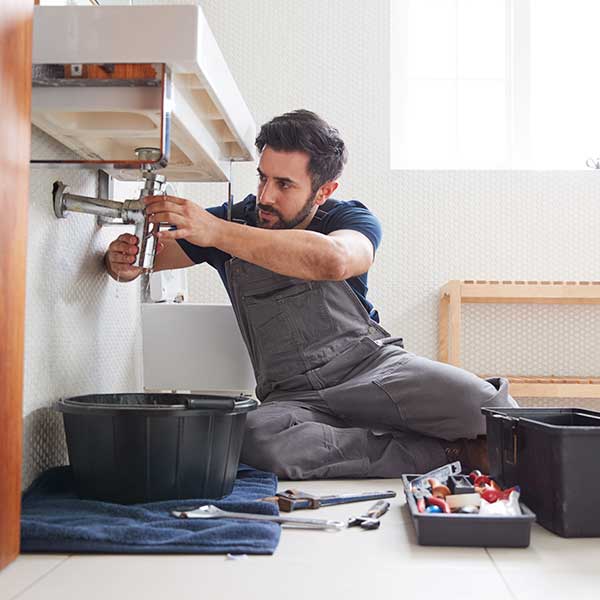 Male Plumber Working To Fix Leaking Sink In Home Bathroom